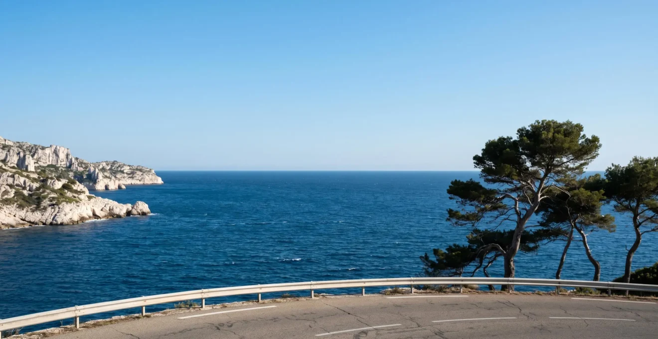 Vue panoramique de la Corniche Kennedy à Marseille avec la mer Méditerranée bleue, des pins parasols et les rochers blancs des calanques